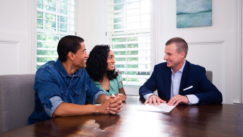 Mark and clients sitting at a table strategizing how to have a successful sale